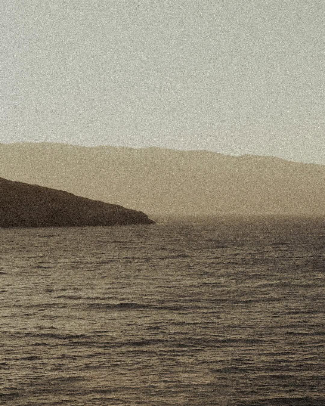 Rivage et collines dans une lumière dorée, vue depuis l'eau